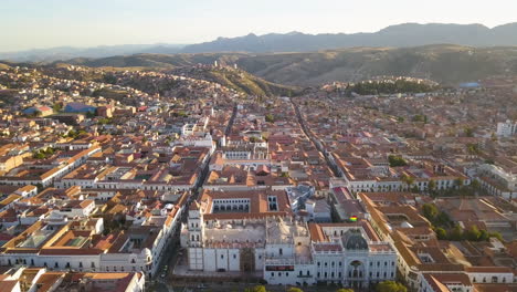 Aerial-view-flying-over-the-scenic,-colonial-city-of-Sucre,-Bolivia-at-sunset