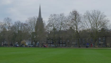Pan-across-trees,-grassy-field,-and-historic-neighborhood-in-Cambridge-England