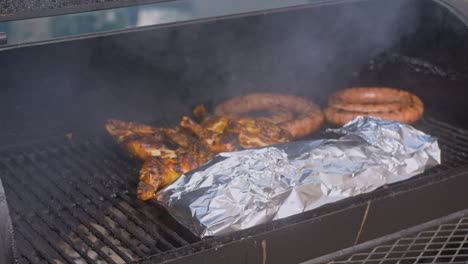 Man-puts-foil-wrapped-ribs-on-to-smoking-BBQ-Pit