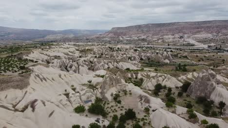 Flying-back-drone-over-rock-formations,-natural-landscapes-of-Cappadocia,-Goreme-in-Turkey