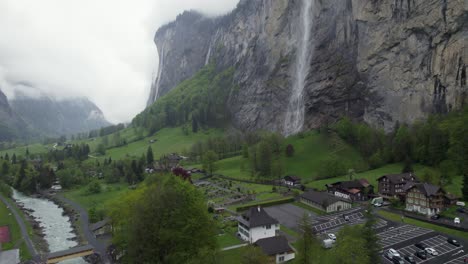 Touristic-Town-of-Lauterbrunnen-with-Beautiful-Waterfall-on-Rainy-Day,-Aerial-Panorama