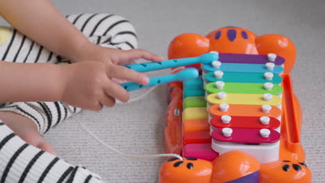 Little-Girl's-Hands-Playing-on-Toy-Piano-Tikes-Jungle-Jamboree-Tiger-Xylophone-At-Home-Sitting-on-Floor---close-up-slow-motion