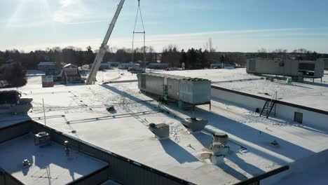 Aerial,-blue-collar-workers-installing-new-HVAC-unit-onto-industrial-building