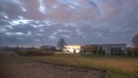 Cozy-modern-home-in-rural-landscape,-cloudscape-flowing-above,-time-lapse