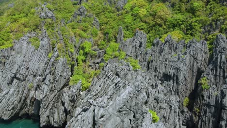 Aerial-View-:-Flying-over-Interesting-Rock-Formations-Surrounding-The-Secret-Beach,-a-tropical-shallow-swimming-lagoon,-Popular-Tourist-attraction-of-Island-hopping-tour-C-in-EL-Nido,-Philippines