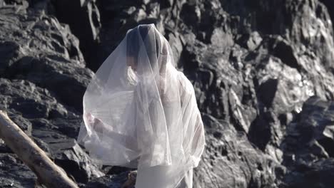 Elegant-Woman-Wearing-White-Bridal-Veil-And-Dress-During-Photoshoot-At-Rocky-Beach