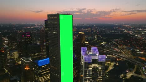 Green-screen-banner-tracked-on-a-skyscraper-wall,-dusk-city-background---VFX-visuals