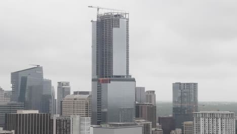 Close-up-drone-parallax-view-of-building-in-downtown-Austin,-Texas-with-tilt-down-to-neighborhood