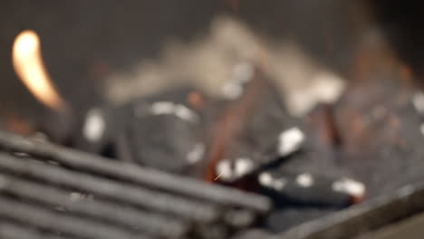 Pan-and-rack-focus-to-burning-charcoal-briquettes-in-BBQ-pit