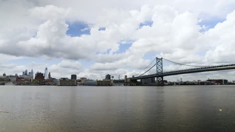Philadelphia-skyline-over-the-calm-Delaware-River-with-the-Benjamin-Franklin-Bridge-on-a-cloudy-warm-day-wide
