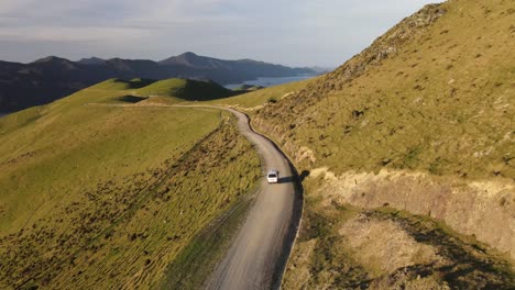 Aerial-Follow-Of-Car-Traveling-On-Mountain-Road-During-Sunset-In-French-Pass-Narrow-In-New-Zealand
