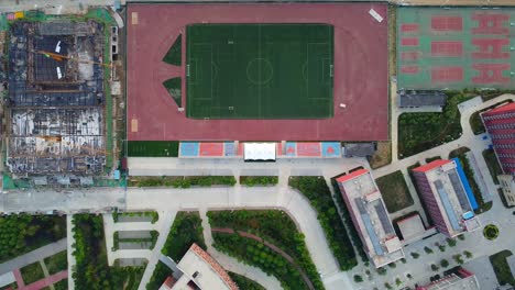 Ascending-aerial-view-of-football-field-at-Beijing-Jiaotong-University,-Weihai