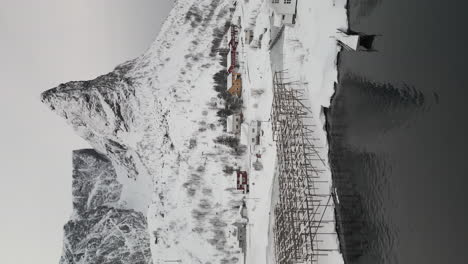 Vertikale-Aufnahme-Einer-Verschneiten-Landschaft-Mit-Bergen,-Steg-Und-Yachthafen-In-Reine,-Lofoten-Im-Winter