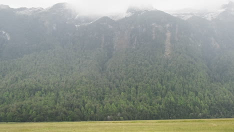 Plano-De-Hierba-Plana-En-Nueva-Zelanda,-Con-Imponentes-Montañas-Envueltas-En-Niebla-En-El-Fondo