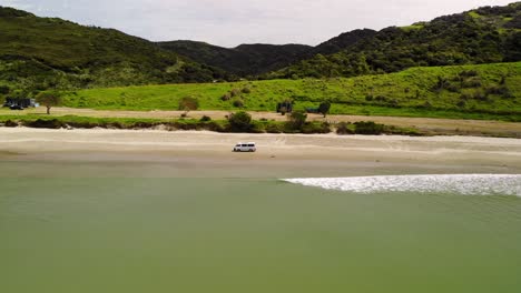 Drone-aerial-of-van-driving-on-sandy-beach-at-New-Zealand-coast