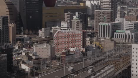 Wide-of-Japanese-Cityscape,-Kokura,-Kitakyushu,-Japan-with-Shinkanzen-Bullet-Train-and-Mountains