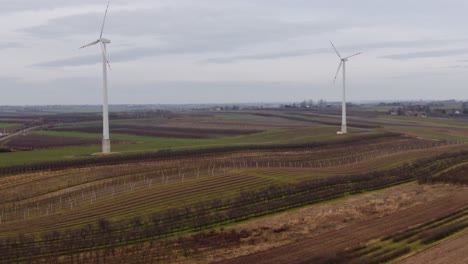 Zwei-Windmühlenturbinen-Auf-Ackerland-In-Polen-Produzieren-Saubere-Elektrische-Energie,-Luftaufnahme