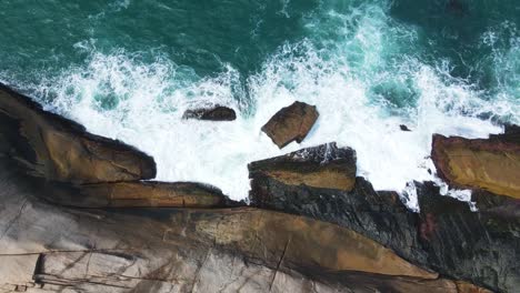 Drone-shot-from-above-of-sea-water-crashing-on-cliff-rocks