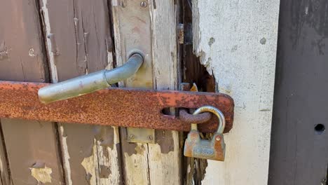4K-60FPS-Rusty-Metal-Bar-and-Vintage-Padlock-Lock-Door-on-Wooden-Hut---Truck-Shot