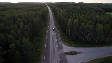 Vista-Aérea-Siguiendo-Un-Coche-Solitario-En-Un-Camino-Forestal-En-El-Norte-De-Finlandia,-Laponia,-Puesta-De-Sol