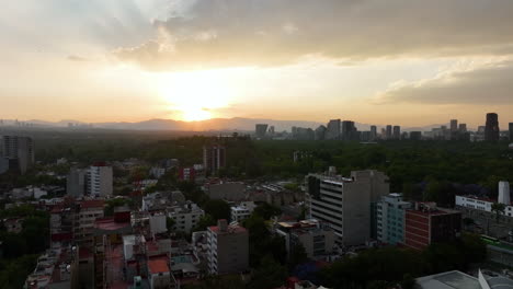 Drone-shot-rising-over-apartments-toward-the-Chapultepec-park,-sunny-evening-in-Mexico-city