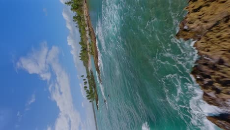 Vertical-Fpv-flight-over-tropical-Islands-wit-waving-Caribbean-sea-and-palm-trees-during-summer---PLAYA-LOS-COQUITOS,-Dominican-Republic