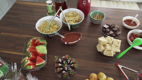 Overhead-Pan-of-Party-Smorgasbord-of-Football-Theme-Snacks-and-Food-on-Table-for-Super-Bowl