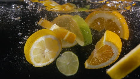 Muchas-Frutas-Cítricas-En-Rodajas-A-Cámara-Lenta-Salpican-Agua-Con-Bebida-De-Burbujas