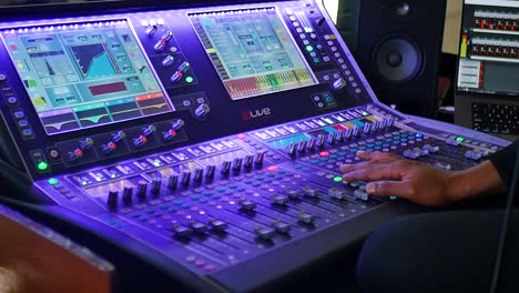 A-medium-shot-capturing-a-hand-operating-an-audio-mixer,-skillfully-adjusting-knobs-and-sliders
