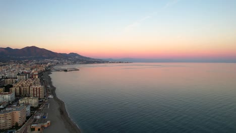 Pastel-sky-over-fuengirola-hills-beach-at-sunrise,-reflect-on-ocean