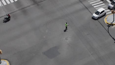 Santo-domingo,-dominican-republic---April-2023---Traffic-officer-stopping-a-vehicle-trying-to-cross-at-a-red-light,-drone-view-in-the-city-of-santo-domingo,-dominican-republic
