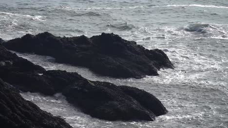 Ocean-waves-crashing-against-rugged-black-rocks