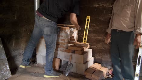 Worker-in-Small-Mud-Hut-Working-to-Install-Brick-Stove-Mason