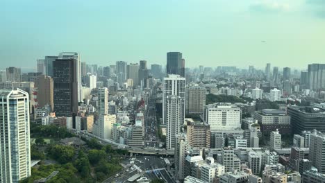 Wide-static-angle-view-of-Tokyo-from-a-building-looking-south-on-a-hot-hazy-summer-day-with-plane-flying-in-the-sky