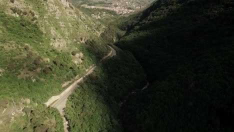 Forward-aerial-view-of-a-road-in-the-valley-into-mountains-leading-to-a-village