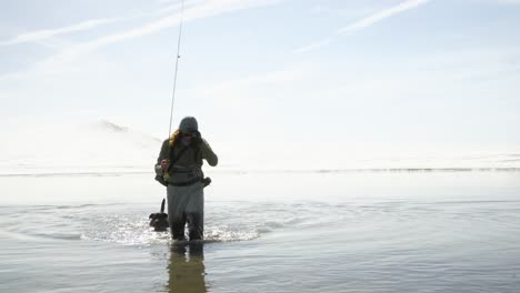 High-key-nature-scene:-Fisherman-and-dog-in-pale-blue-mountain-lake