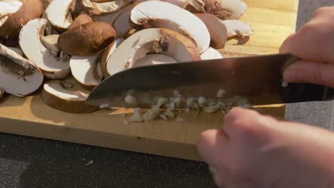 Close-up-of-garlic-and-fresh-mushrooms-being-sliced-by-a-woman-hand-preparing-a-healthy-recipe