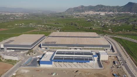 Industrial-Warehouses-Distribution-Center-With-Mountains-and-Village-in-the-Background