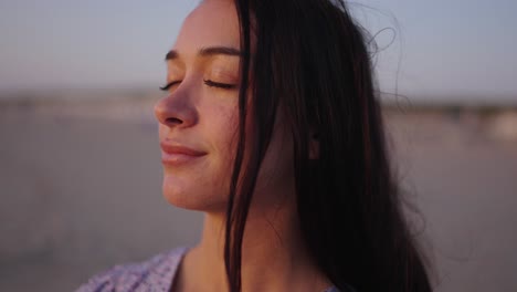 Portrait-shot-of-brunette-woman-enjoying-golden-sunset-time-at-beach-in-Netherlands---Feel-the-wind-and-sunshine---Close-up