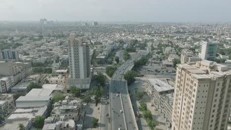 Vista-Aérea-De-La-Carretera-Shahra-e-qaideen-En-El-Mercado-De-Karachi-En-Un-Día-Soleado-Y-Apartamentos-Residenciales-De-Gran-Altura