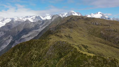 Mujer-Joven-En-La-Cresta-De-La-Montaña-Revelación-Aérea-Del-Impresionante-Paisaje-Alpino-De-Las-Altas-Montañas-En-Nueva-Zelanda