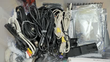 Proceeding-to-put-away-many-computer-and-hifi-cables-in-a-plastic-storage-box-and-closing-the-lid