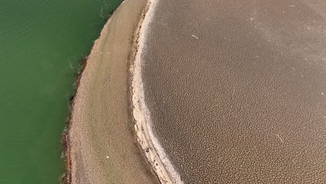 Curved-Sau-reservoir-shoreline-contrasting-dry-arid-low-drought-water-terrain-and-shimmering-blue-green-river-Ter