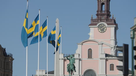 Swedish-flags-waving-in-the-wind,-in-front-of-Storkyrkan,-Old-town,-Stockholm