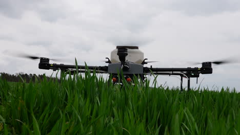 Agriculture-Drone-With-Tank-Landing-in-Green-Farming-Field,-Close-Up