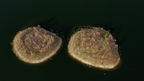 Aerial-Tilt-up-Of-Two-Islands-Surrounded-By-Calm-Lake-Waters
