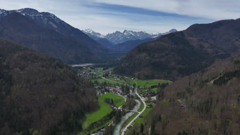 Aerial-View-of-Scenic-Austrian-Alps-Landscape,-Green-Valley-Village-and-Snow-Capped-Peaks-on-Sunny-Spring-Day