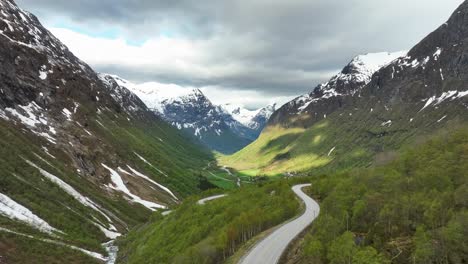 Aerial-presenting-Hjelledalen-valley-in-Stryn-and-Norfjord-area-Norway---Aerial-above-road-with-scenic-valley-and-snow-capped-mountains-in-background
