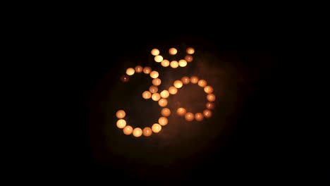 Om-symbol-from-burning-candles-with-smoke-movement-on-black-background