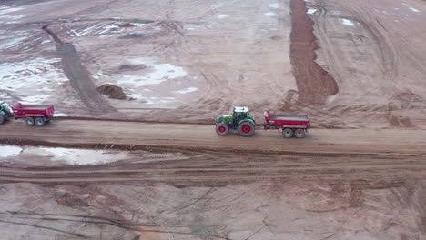 Drone-footage-following-a-tractor-with-empty-trailer-on-a-construction-site